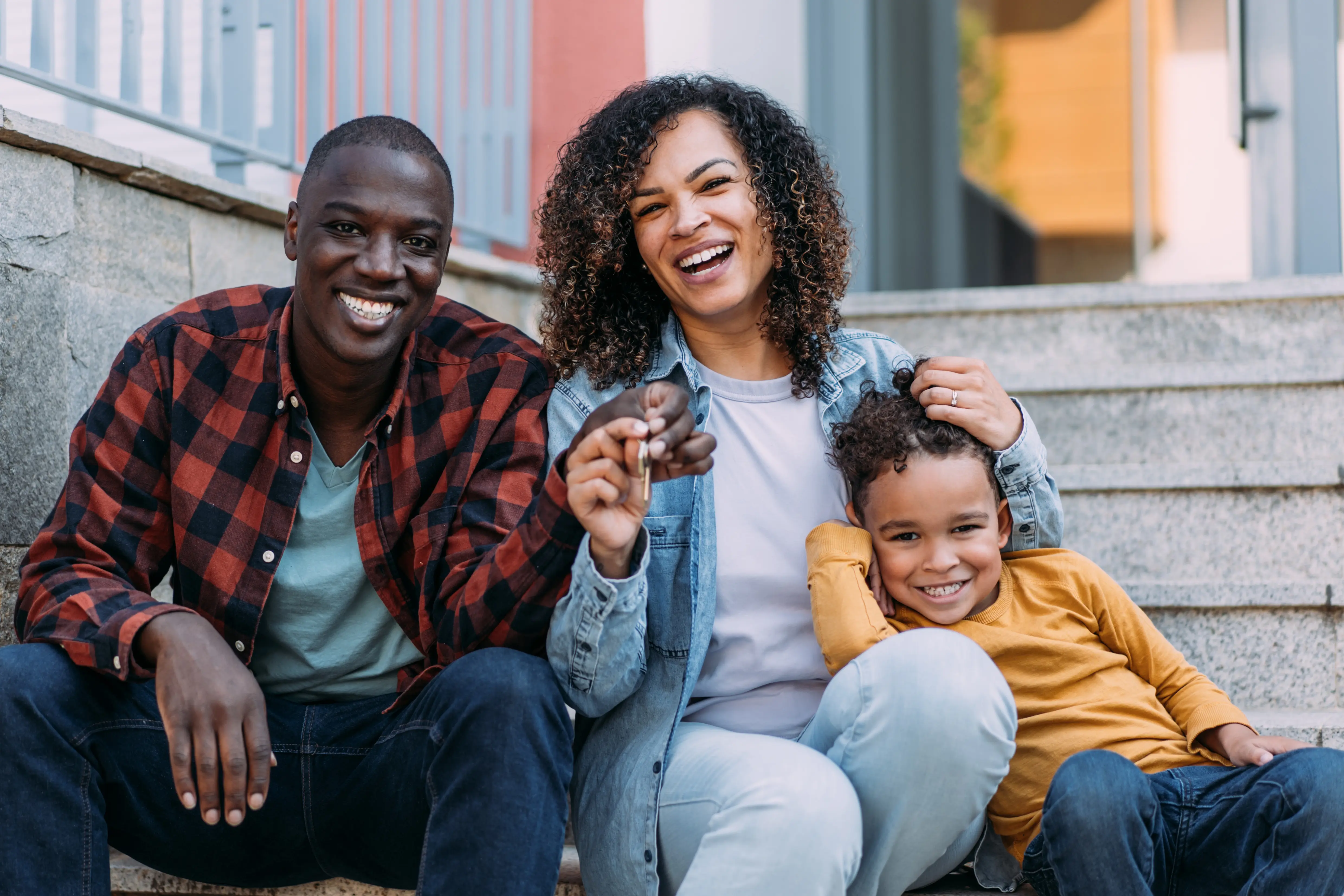 Father holding child with mother smiling beside them